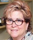 Headshot of Beth Mineo. Beth is an adult female with short blonde hair and is wearing glasses.