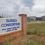 The sign for the new Sussex Consortium school, with the campus in the background