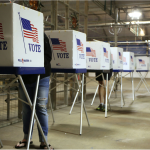 A line of temporary tables with voting blinds in a warehouse.