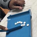 A pharmacists uses a tray to sort pills.