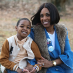 LeTonya Wilson-Nalley has dark toned skin and a dark bob and wears a fashionable denim blazer and faux fur collar. Her seven year old son, Nafis, has dark toned skin and a gap-toothed smile. He wears a turtleneck and letterman's jacket.