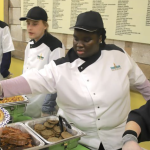 Students in the Food Bank's Kitchen School serve food from buffet-style trays.