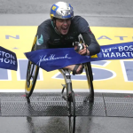 Marcel Hug crossing the 127th Boston Marathon finish line in a racing wheelchair.