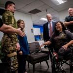 A group of people including a person in camo and Sen. Tammy Duckworth