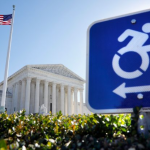 Sign with icon of a person in a wheelchair and arrow and the U.S. flag outside of the Supreme Court of the U.S.